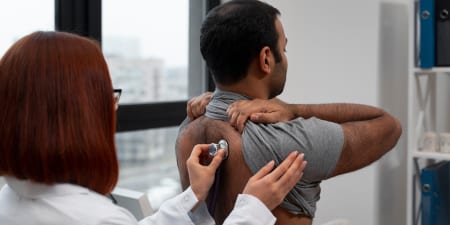 A health professional examining a male patient.