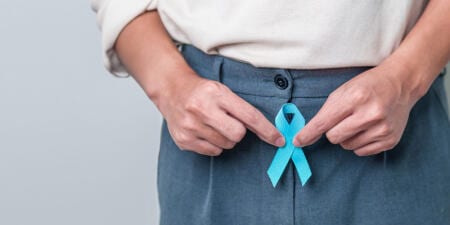 A male patient showing a blue ribbon to raise awareness about penile cancer.
