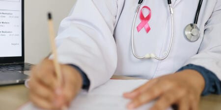 An urologist with a pink ribbon pined to the coat illustrate bladder cancer diagnosis.