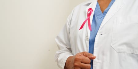 A pink ribbon pinned on a doctor's coat for awareness against prostate cancer.
